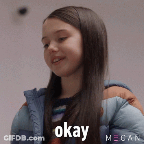 A Girl In A Blue Jacket Says Okay In Front Of A Megan Logo GIF