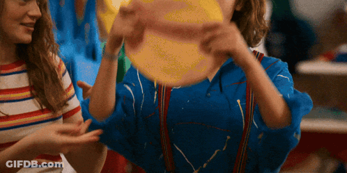 A Girl In A Blue Shirt Is Holding A Yellow Ball GIF
