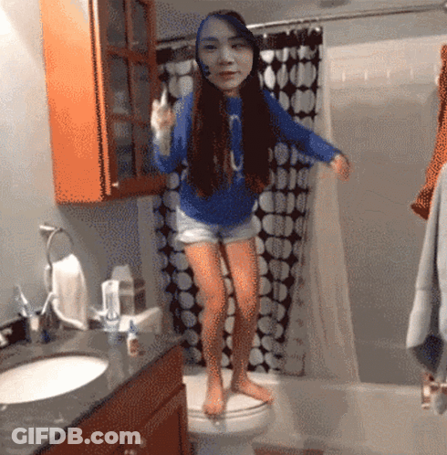 A Girl In A Blue Shirt With The Letter O On It Is Standing On A Toilet GIF