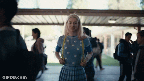 A Girl In A Blue Top And Plaid Skirt Is Holding A Yellow Ribbon GIF