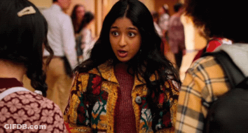 A Girl In A Colorful Jacket Is Talking To Another Girl In A Plaid Shirt GIF