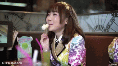 A Girl In A Colorful Outfit Is Eating A Piece Of Cake GIF