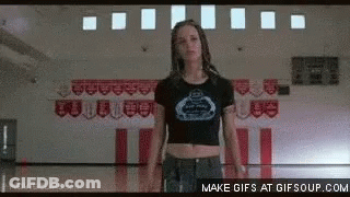 A Girl In A Crop Top Is Standing In A Gym . GIF
