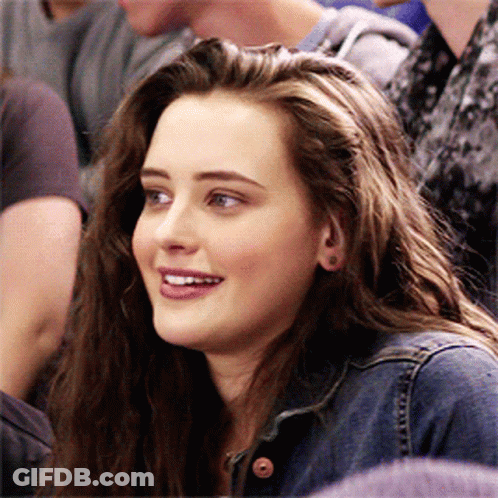 A Girl In A Denim Jacket Is Smiling In A Crowd GIF