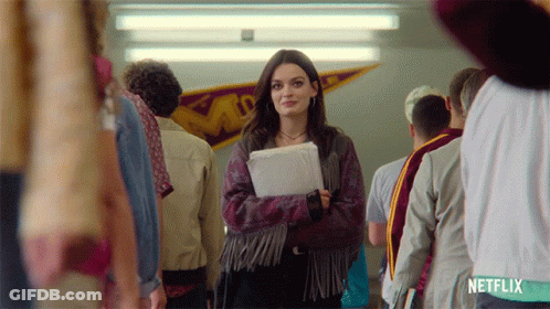 A Girl In A Fringed Jacket Is Standing In A Hallway With Netflix Written On The Bottom GIF