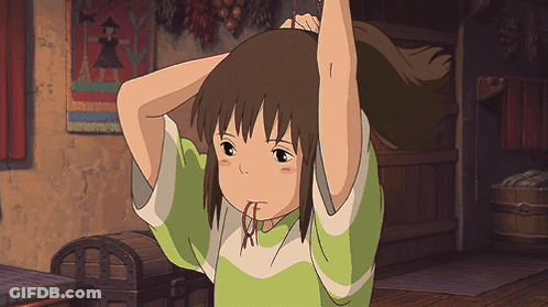 A Girl In A Green Shirt Holds Her Hair Up In A Room GIF