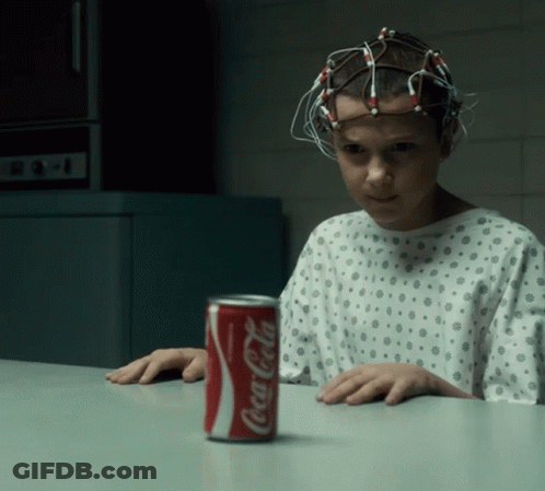 A Girl In A Hospital Gown Sits At A Table With A Can Of Coca Cola On It GIF