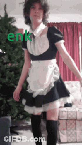 A Girl In A Maid Costume Is Standing In Front Of A Christmas Tree With The Word Enk Written In Green GIF