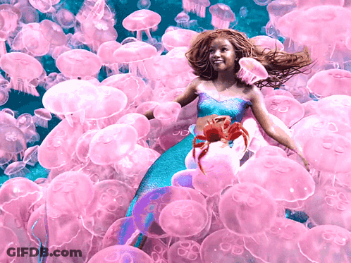 A Girl In A Mermaid Costume Is Surrounded By Jellyfish GIF