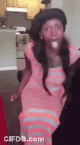 A Girl In A Pink Dress And Hat Is Standing In A Kitchen . GIF