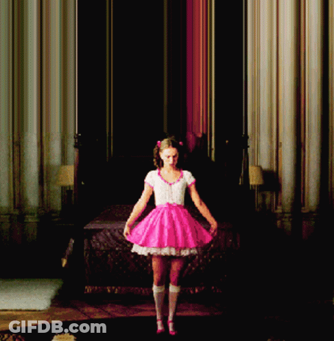 A Girl In A Pink Dress Is Standing In A Room GIF
