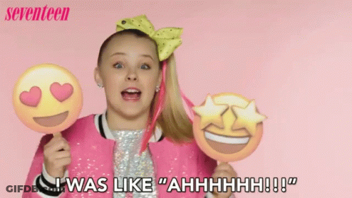 A Girl In A Pink Jacket Is Holding Two Emojis And Says " I Was Like Ahhhh !!! " GIF