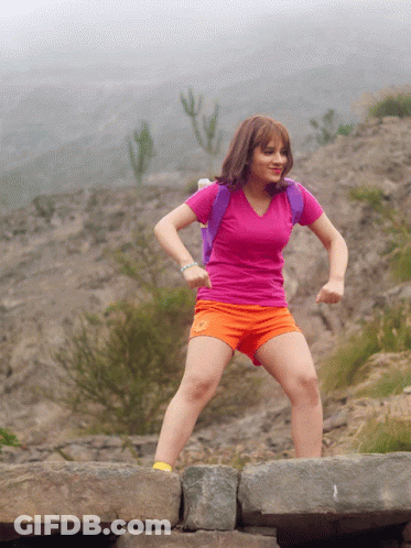 A Girl In A Pink Shirt And Orange Shorts Is Jumping On A Rock GIF