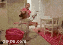 A Girl In A Pink Shirt Is Playing With A Toy Stroller GIF