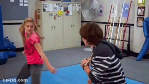 A Girl In A Pink Shirt Is Standing Next To A Boy In A Black And White Striped Shirt GIF