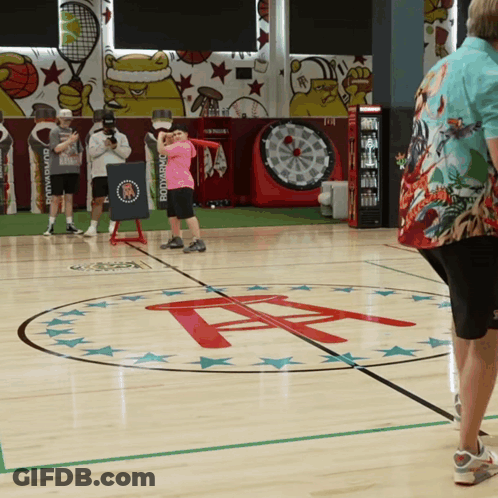 A Girl In A Pink Shirt Is Standing On A Basketball Court GIF
