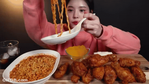 A Girl In A Pink Sweatshirt Is Eating Noodles And Chicken GIF