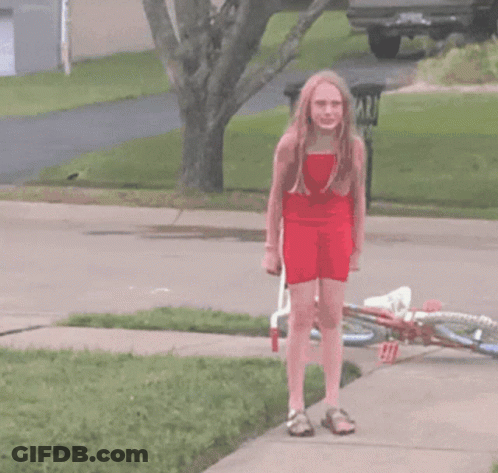 A Girl In A Red Dress Is Walking Past A Trash Can That Says Yard On It GIF