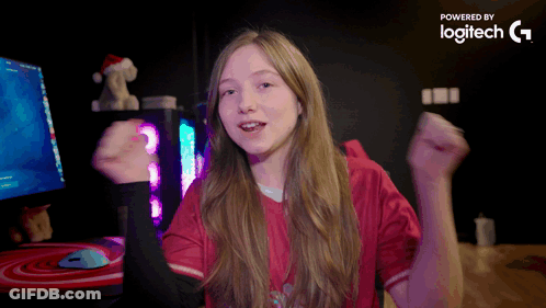 A Girl In A Red Shirt Is Dancing In Front Of A Computer Monitor Which Is Powered By Logitech G GIF