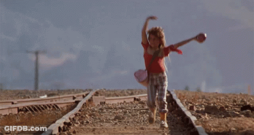A Girl In A Red Top Is Running On Train Tracks GIF