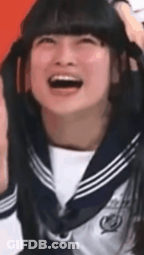 A Girl In A Sailor Uniform Is Laughing And Holding Her Hair GIF