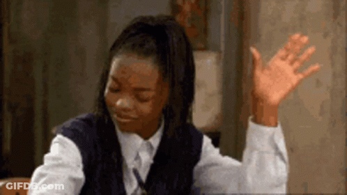 A Girl In A School Uniform Is Sitting At A Desk With Her Hand Up In The Air . GIF