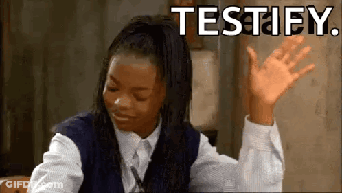 A Girl In A School Uniform Is Sitting At A Desk With Her Hands In The Air And The Words Testify Written Above Her . GIF
