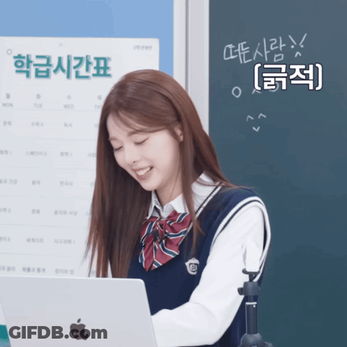 A Girl In A School Uniform Is Smiling While Looking At An Apple Laptop GIF