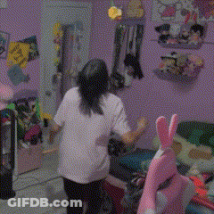 A Girl In A White Shirt Is Standing In A Room With A Stuffed Animal GIF