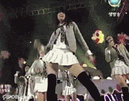 A Girl In A White Skirt And Black Knee High Socks Is Dancing On Stage GIF