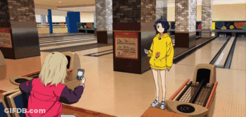 A Girl In A Yellow Hoodie Is Standing In A Bowling Alley GIF