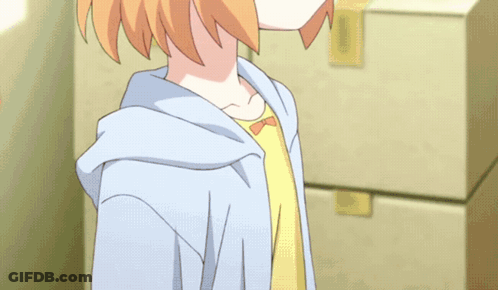 A Girl In A Yellow Shirt And A Blue Hoodie Stands In Front Of A Stack Of Boxes GIF