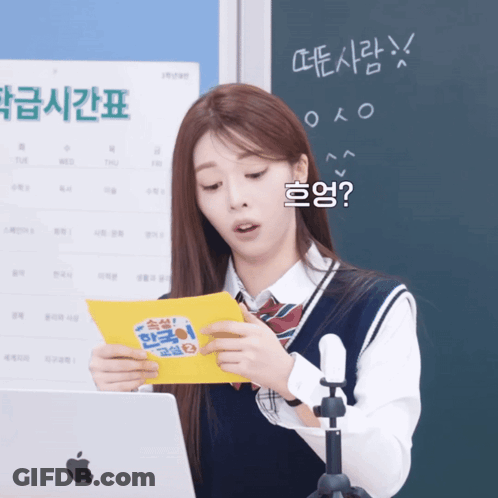 A Girl In Front Of An Apple Laptop Holds A Yellow Piece Of Paper GIF