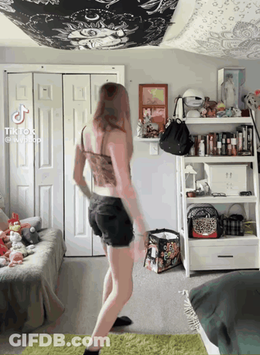 A Girl Is Dancing In A Bedroom With A Bag That Says ' O'neill ' On It GIF