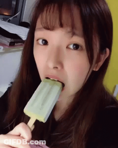 A Girl Is Eating An Ice Cream Bar With A Green Flavor GIF