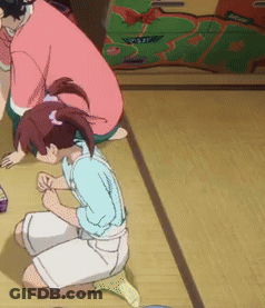 A Girl Is Kneeling Down On The Floor While A Man Sits Behind Her GIF
