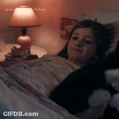 A Girl Is Laying In Bed With A Lamp And The Words La Guardia Festival On The Bottom Right GIF