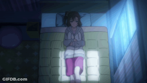 A Girl Is Laying On A Bed With A Blue Light Shining On Her GIF