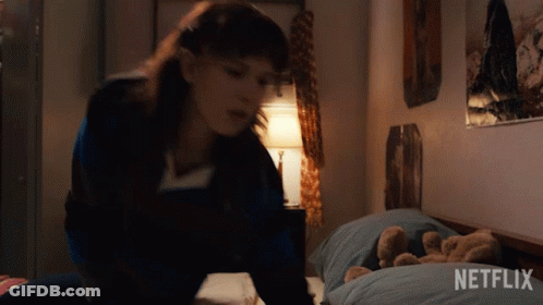 A Girl Is Laying On A Bed With A Teddy Bear And A Netflix Logo In The Corner . GIF