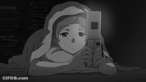 A Girl Is Laying Under A Blanket Holding A Cell Phone . GIF