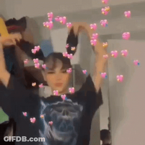 A Girl Is Making A Heart Shape With Her Hands In Front Of A Mirror . GIF
