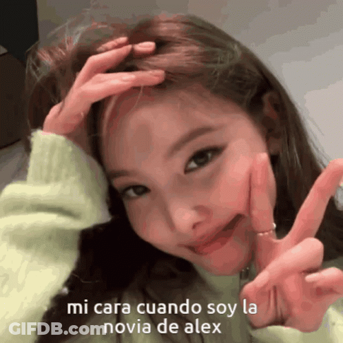 A Girl Is Making A Peace Sign With Her Hands On Her Head GIF