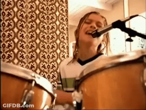 A Girl Is Playing Drums And Singing Into A Microphone . GIF