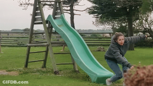 A Girl Is Playing On A Green Slide In A Grassy Field GIF