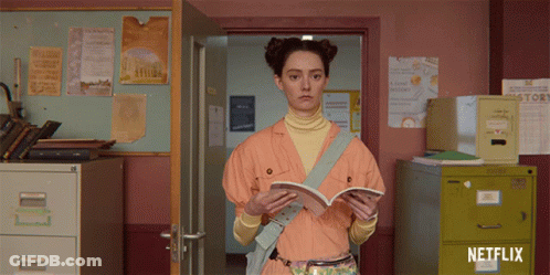 A Girl Is Reading A Book In A Room With A Netflix Logo GIF