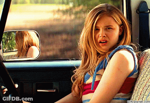 A Girl Is Sitting In The Back Seat Of A Car With A Surprised Look On Her Face .. GIF