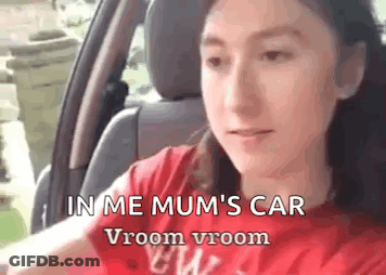 A Girl Is Sitting In The Driver 'S Seat Of A Car . GIF