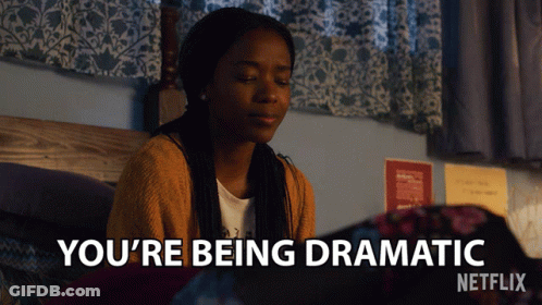 A Girl Is Sitting On A Bed With The Words You 'Re Being Dramatic Above Her GIF
