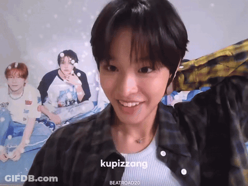 A Girl Is Smiling In Front Of A Poster That Says Kupizzang On It GIF