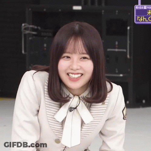 A Girl Is Smiling In Front Of A Sign That Says No GIF